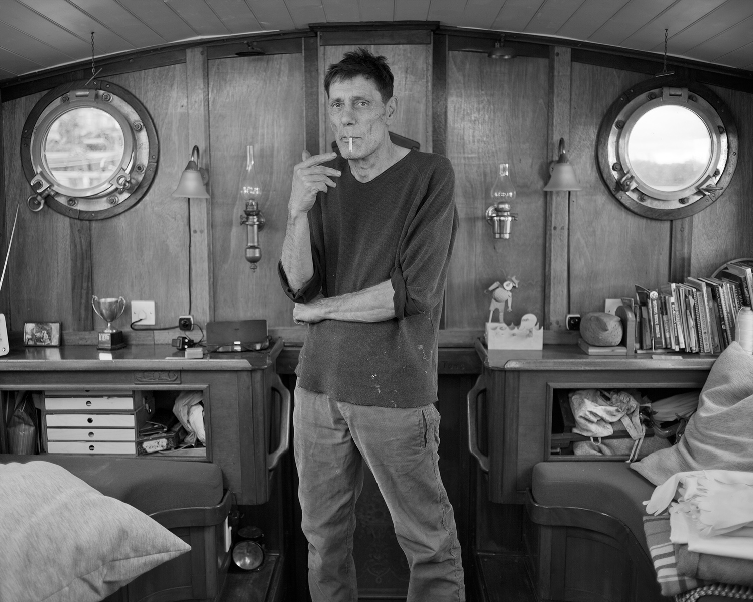 Portrait noir et blanc d'un homme fumant une cigarette dans son bateau sur un mooring de la Tamise Londres.